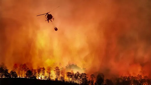 Helikopter bestrijdt een grote bosbrand boven brandend landschap